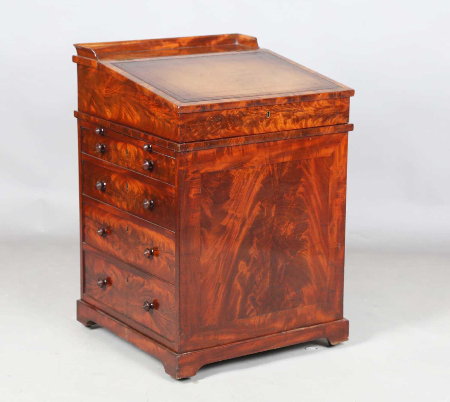 A good early Victorian flame mahogany Davenport, the hinged writing slope inset with tooled