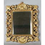 An early 20th century Continental giltwood wall mirror with a carved foliate frame and bevelled