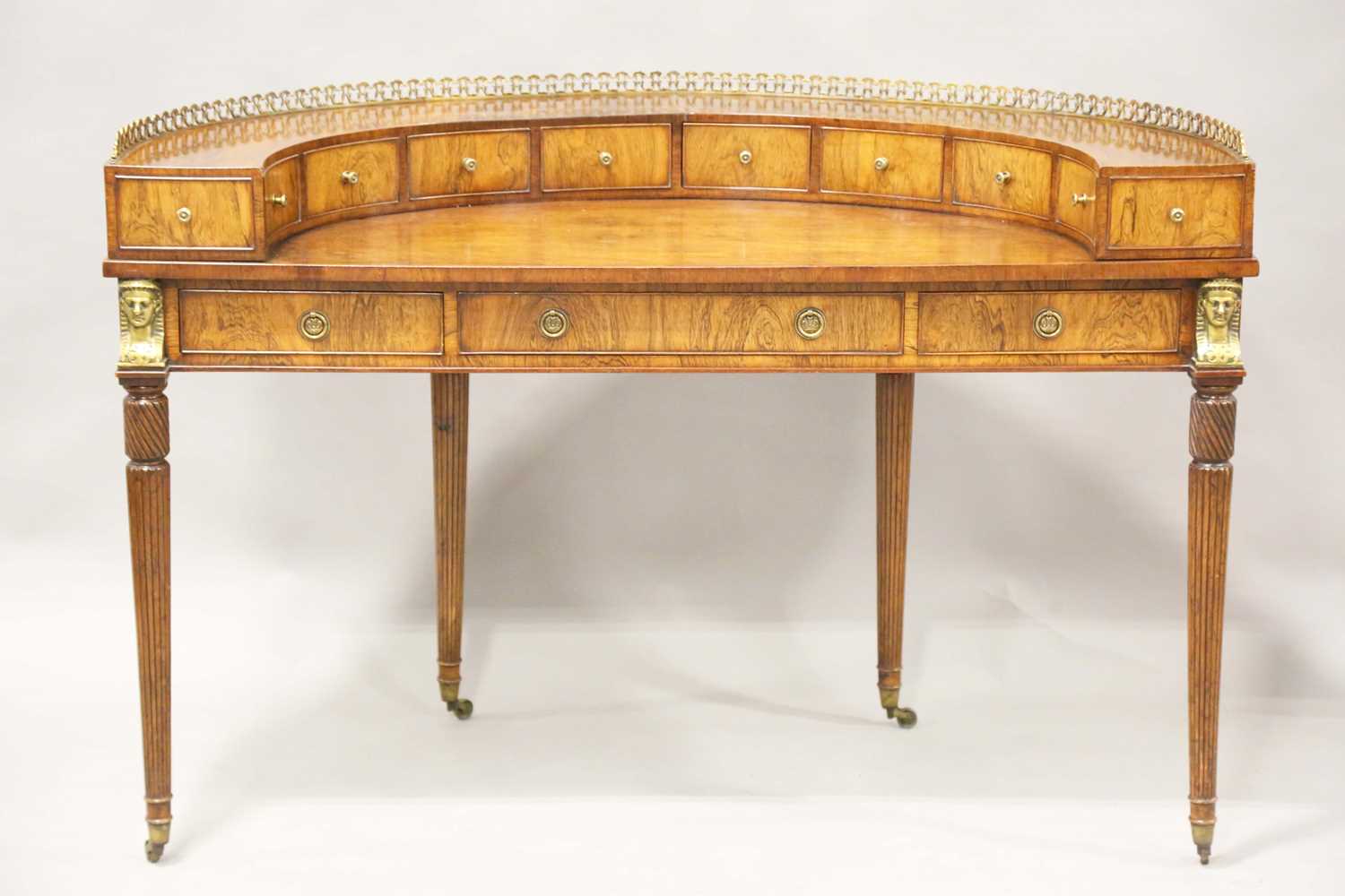 A 20th century reproduction walnut Carlton House style demi-lune desk, the gallery back with gilt