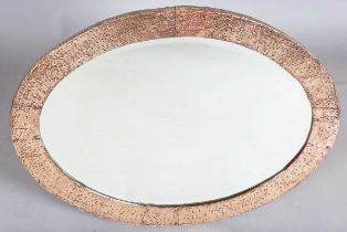 An early 20th century Arts and Crafts hammered copper oval wall mirror with riveted panels and