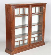 An Edwardian Arts and Crafts walnut and oak glazed bookcase, the two doors inset with curved and