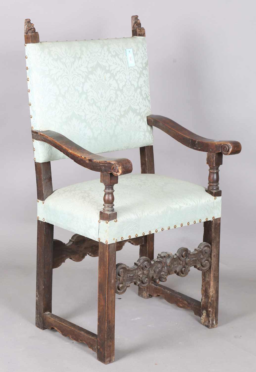 A late 17th century Continental walnut armchair, the finials carved with masks, the two front legs