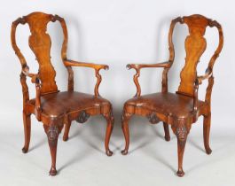 A pair of early 20th century Queen Anne style walnut vase back elbow chairs with brown leather