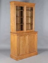 An Edwardian pale oak bookcase cabinet, the glazed top above two doors, height 213cm, width 107cm,