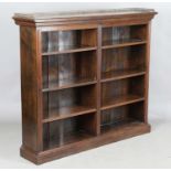 An Edwardian walnut two-section open bookcase with a brass three-quarter gallery, on a plinth
