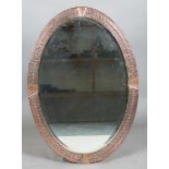 An early 20th century Arts and Crafts copper oval wall mirror with riveted panels and raised dot