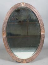 An early 20th century Arts and Crafts copper oval wall mirror with riveted panels and raised dot