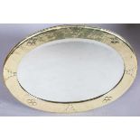 An early 20th century Arts and Crafts brass oval wall mirror with riveted panels and raised