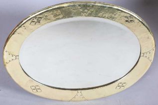 An early 20th century Arts and Crafts brass oval wall mirror with riveted panels and raised