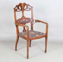 An Edwardian Art Nouveau mahogany framed elbow chair, the pierced back inlaid with a stylized flower