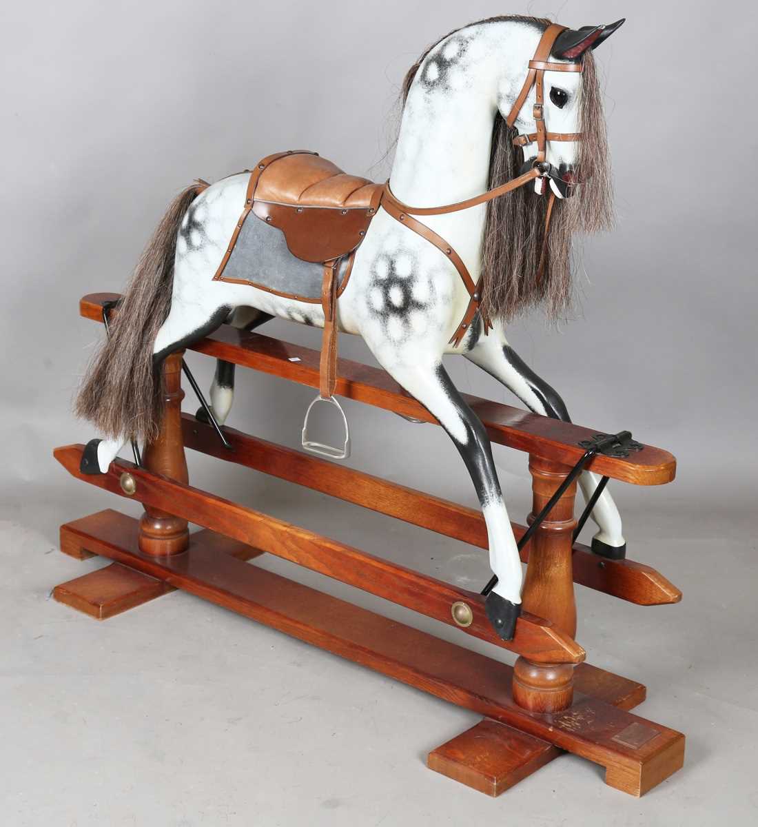 A modern dapple grey rocking horse by Stevenson Brothers, the oak trestle stand bearing plaque