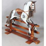 A modern dapple grey rocking horse by Stevenson Brothers, the oak trestle stand bearing plaque