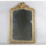 A late 19th century gilt composition arched overmantel mirror with a foliate scroll surmount and