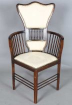 An Edwardian Arts and Crafts style stained walnut showframe armchair, upholstered in cream fabric,