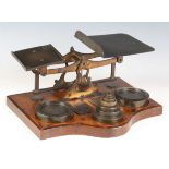 A large late Victorian brass set of postal scales, raised on an oak serpentine front base, holding a