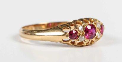 An Edwardian 18ct gold, ruby and diamond ring, mounted with three cushion shaped rubies with two