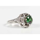 A platinum, demantoid garnet and diamond ring, claw set with the circular cut green demantoid garnet