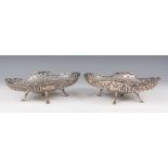 A pair of George V silver baskets of shaped oval form with pierced scrollwork sides, on scroll feet,