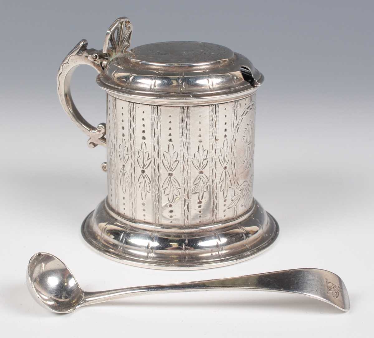 A Victorian silver cylindrical mustard with domed hinged lid and pierced thumbpiece, flanked by a