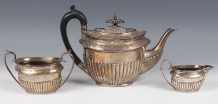 A late Victorian silver oval half-reeded three-piece tea set with engraved decoration, comprising