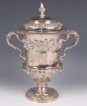 A George IV silver trophy cup and domed cover with foliate finial, the urn shaped body cast with a