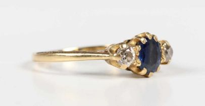An 18ct gold, sapphire and diamond ring, claw set with the oval cut sapphire between two old cut