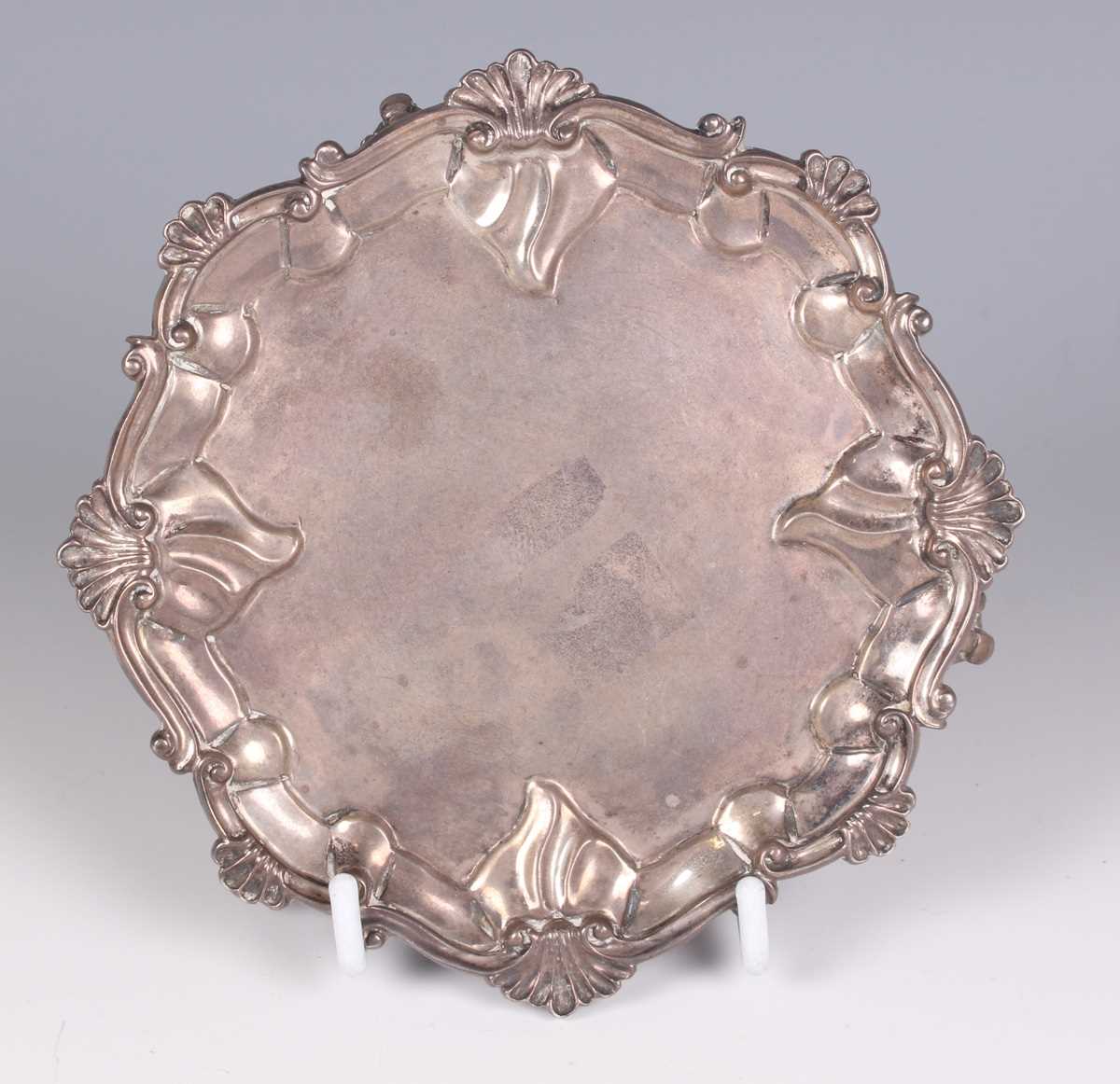 A late Victorian silver shaped circular card salver with cast scallop shell and scroll rim, on