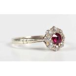 A gold, ruby and diamond cluster ring, claw set with the cushion cut ruby within a surround of eight