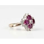 A gold, ruby and diamond cluster ring, claw set with principal circular cut diamond within a