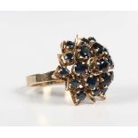 A gold and sapphire cluster ring in a stylised tiered flowerhead shaped design, detailed ‘18K’,