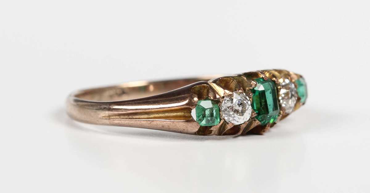 A gold, diamond and green gem set ring, mounted with two old cut diamonds between three green