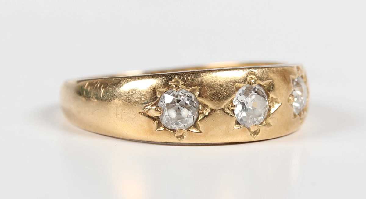 A gold and diamond three stone gypsy ring, mounted with old cut diamonds, detailed ‘18ct’, weight