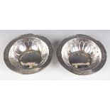 A pair of Arts and Crafts silver circular bowls, each side decorated in relief with petals forming a