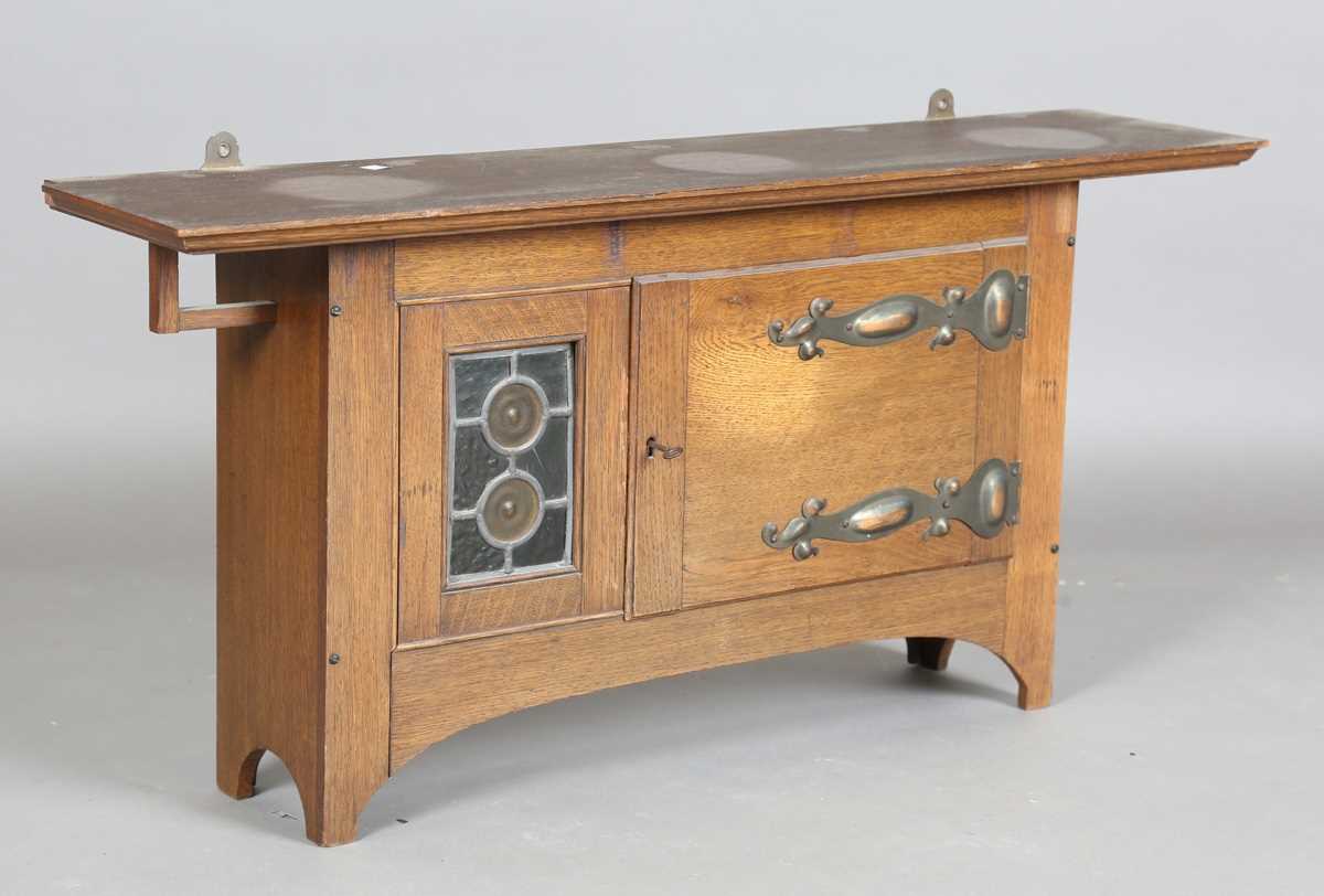 An Edwardian Arts and Crafts oak wall cabinet, in the manner of Liberty & Co, with coppered hinge