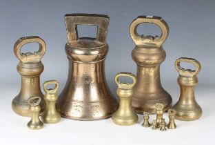 A large 40lbs brass bell weight and a group of eleven other smaller bell weights.