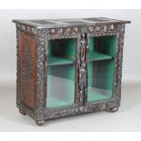 A late 19th century Continental stained oak cabinet, profusely carved with foliage, masks and