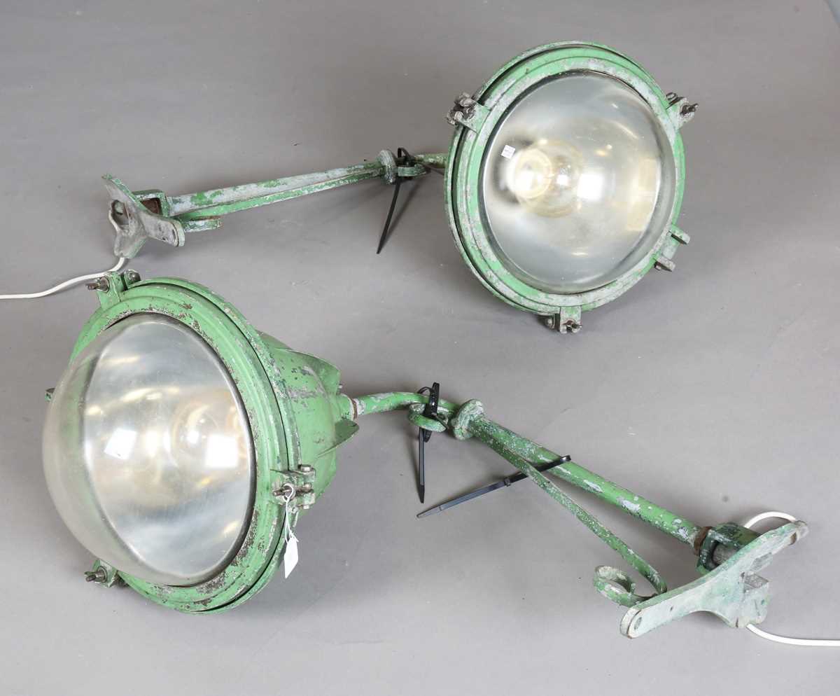 A pair of mid-20th century cast metal railway station wall lights with domed glass shades,