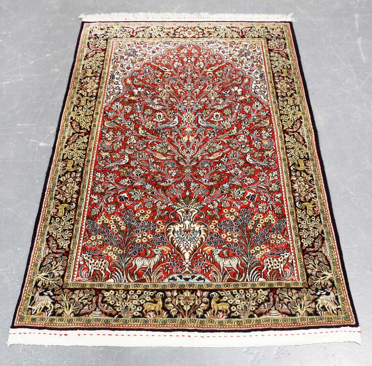 A Qum part silk prayer rug, Central Persia, late 20th century, the red mihrab with an ascending vase