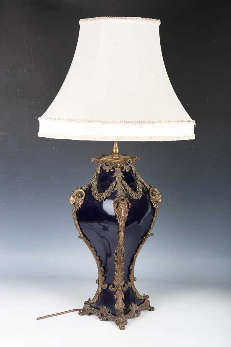 A modern blue glazed porcelain and brass mounted table lamp with ram's head and foliate mounts,