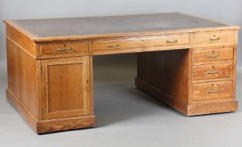 An early 20th century oak partners desk, fitted with an arrangement of drawers and two cupboard
