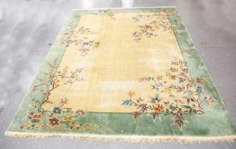 A large Chinese carpet, mid-20th century, the ivory field and green border sparsely decorated with