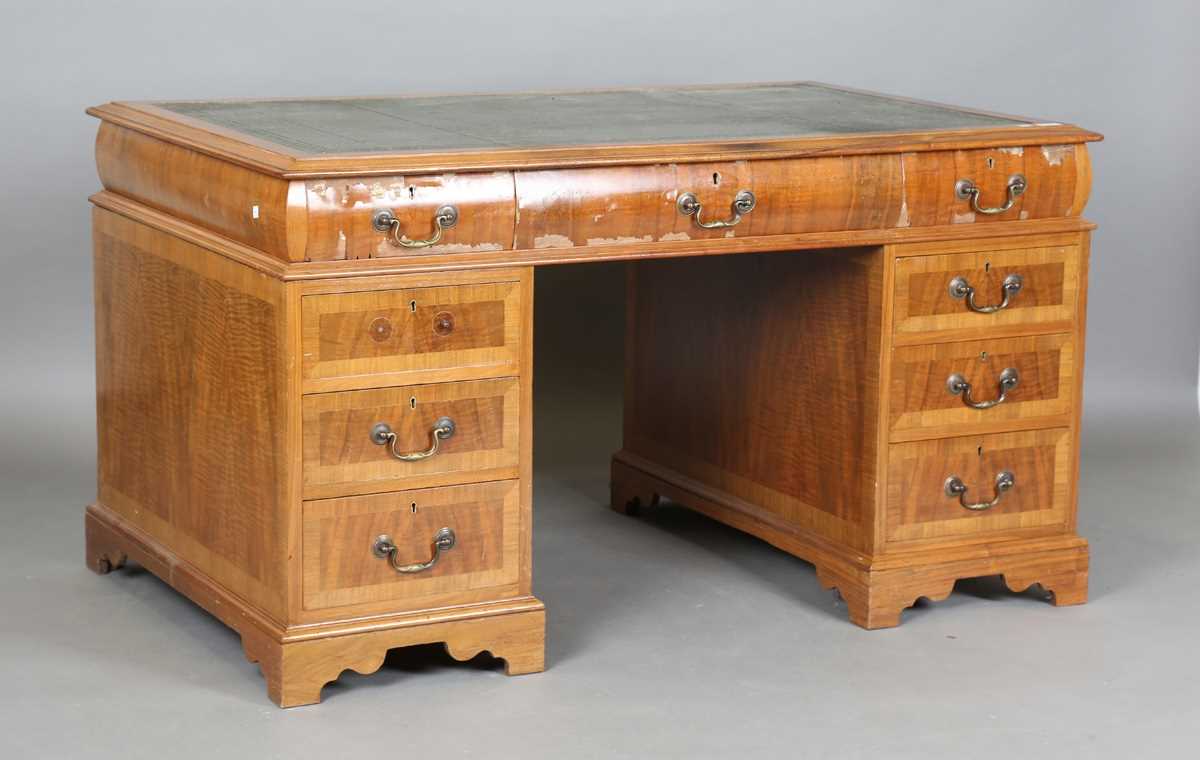 An early/mid-20th century walnut twin-pedestal desk, the top inset with green leather above an
