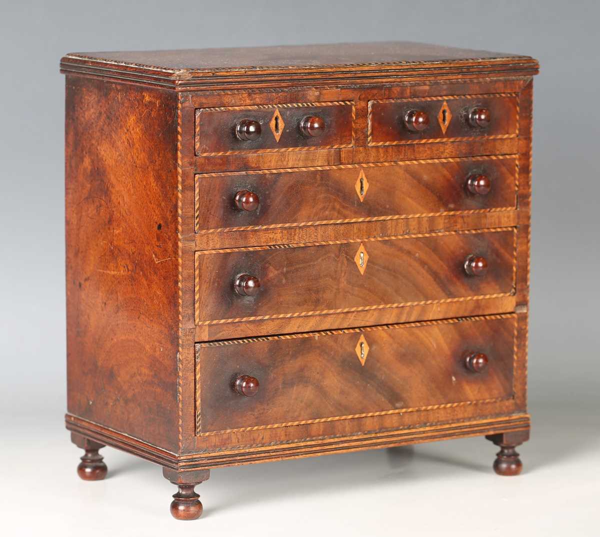 A George III mahogany table-top chest of drawers, possibly an apprentice piece, with overall chequer
