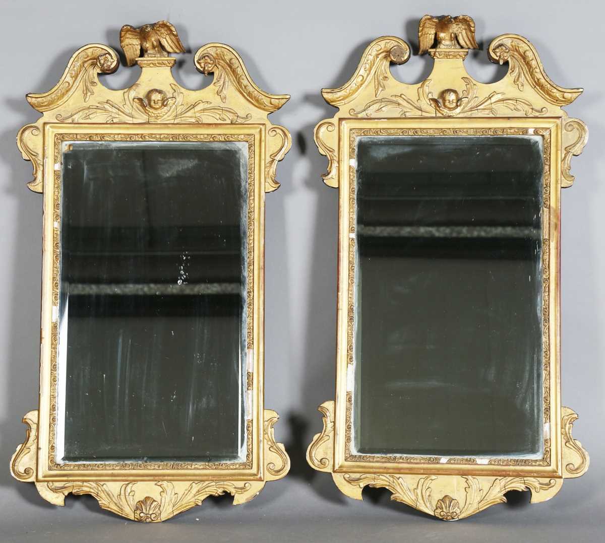 A pair of early 20th century George III style gilt composition wall mirrors, the swan neck pediments