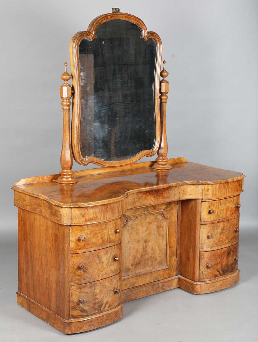 A mid-Victorian burr walnut kneehole dressing table, fitted with a swing mirror above an arrangement