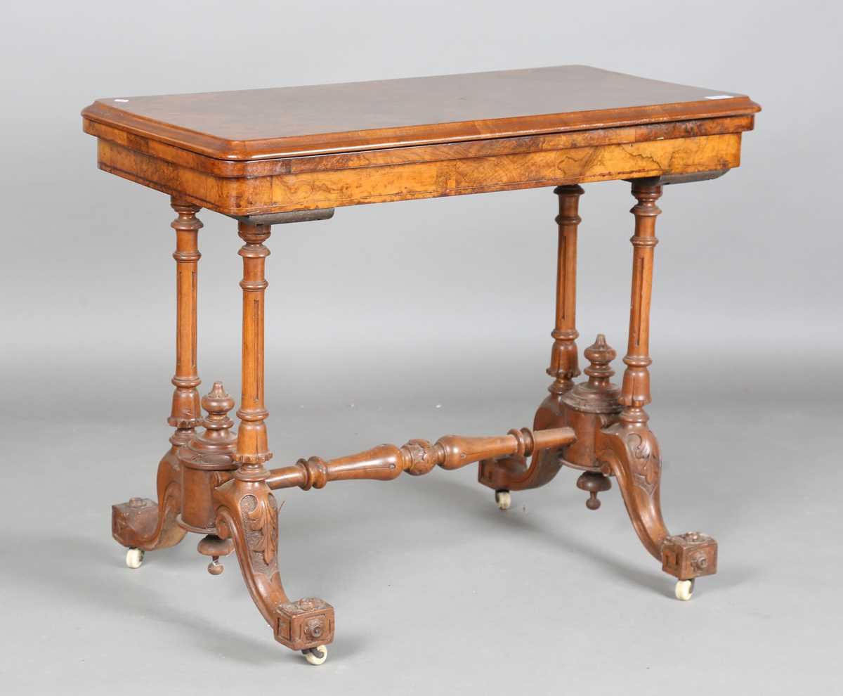 A mid-Victorian burr walnut rectangular fold-over card table, raised on fluted legs and carved feet,