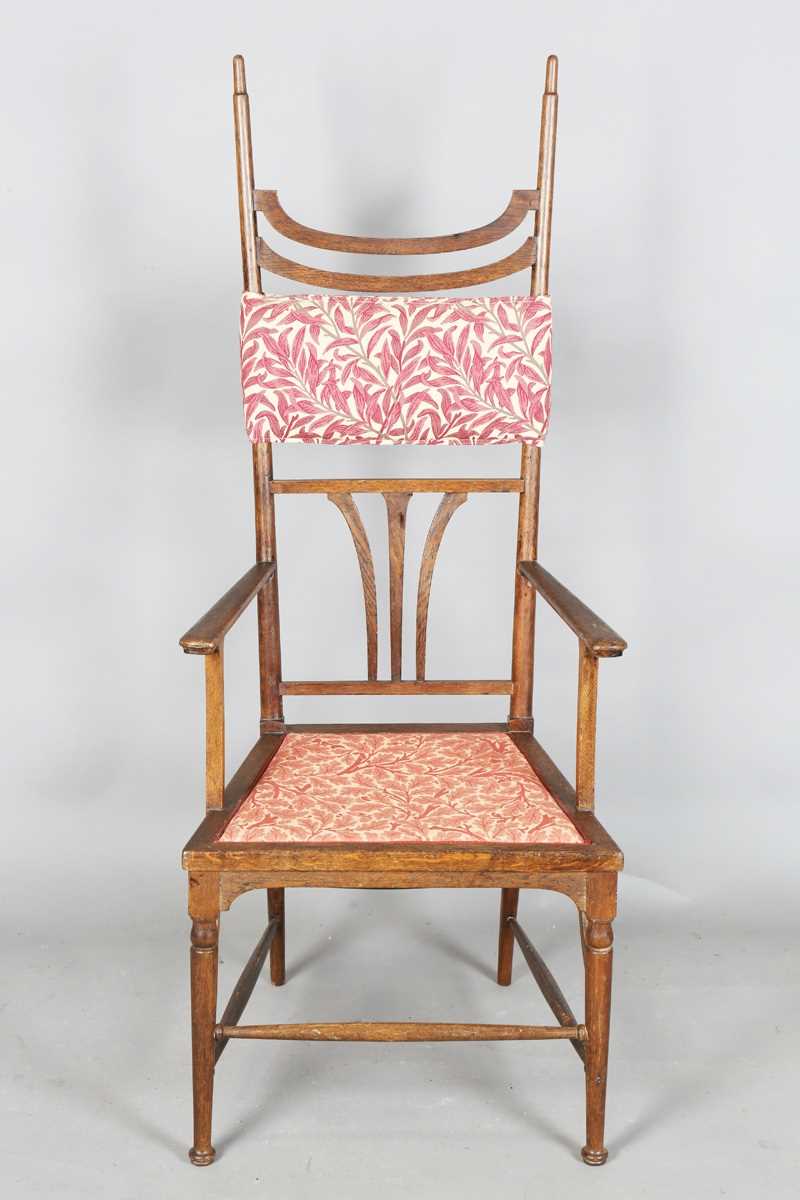 An Edwardian Arts and Crafts oak framed elbow chair, attributed to J.S. Henry, with later fitted