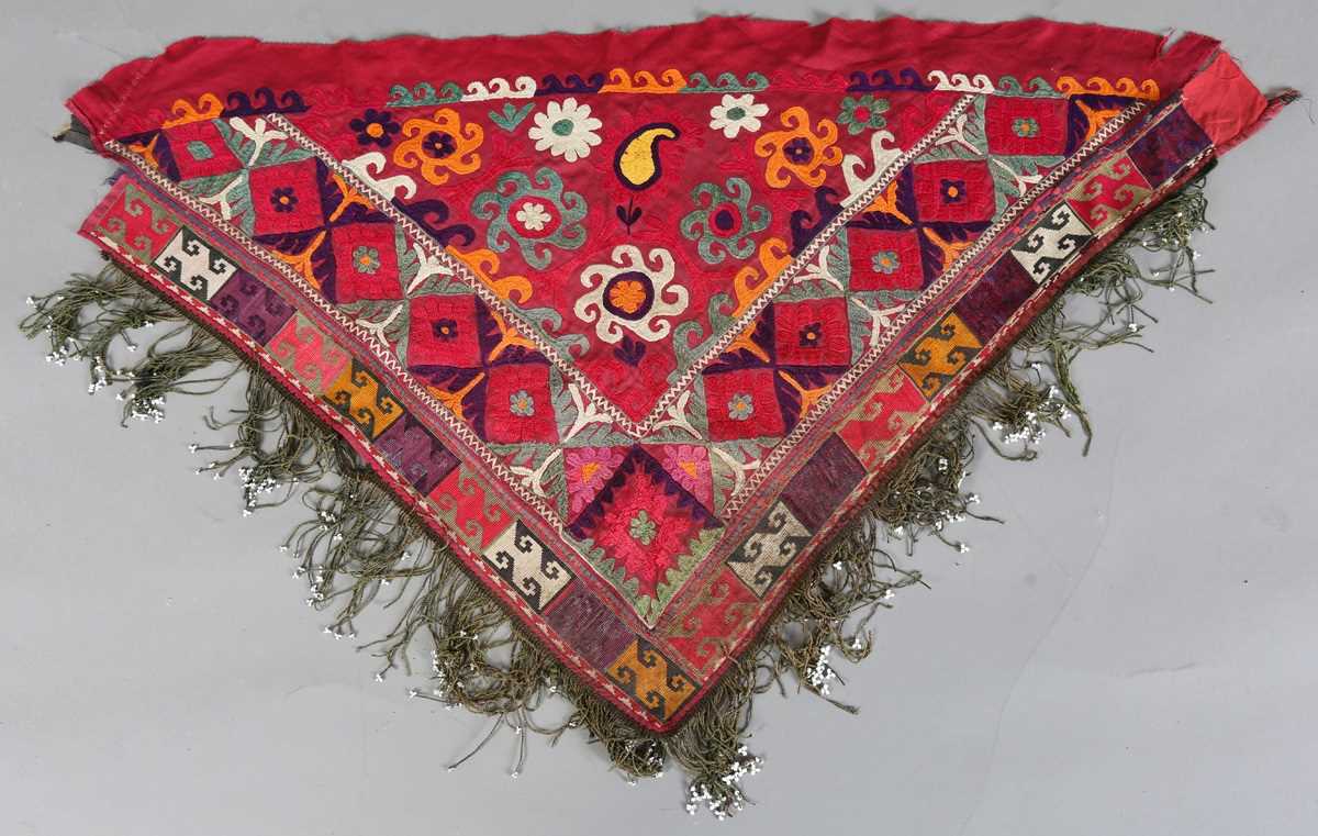 An Uzbekistan silk embroidered suzani, the triangular panel finely worked with scrolling