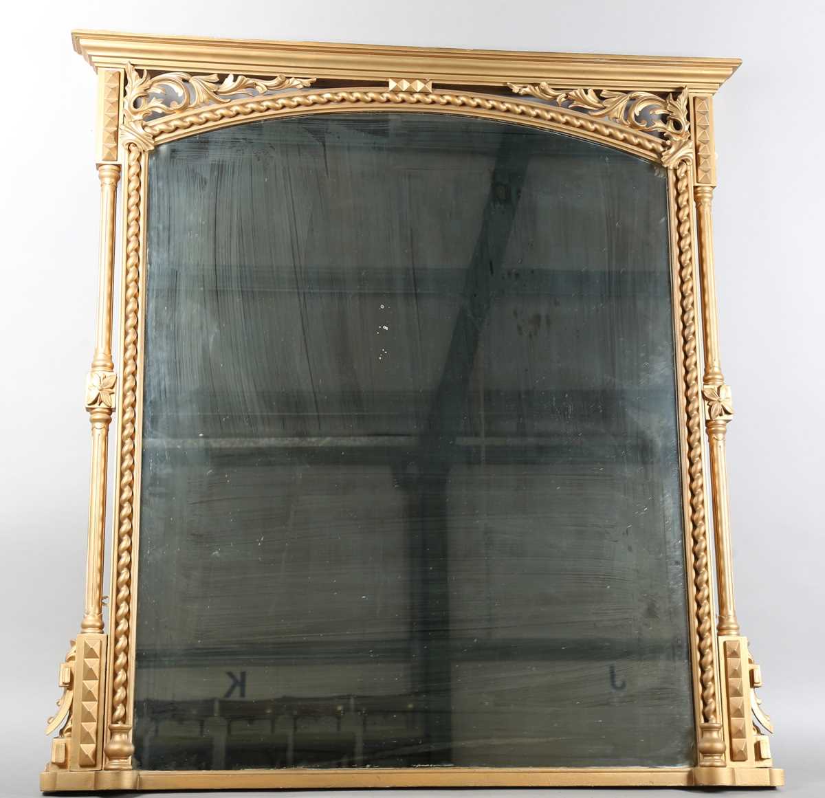A late Victorian gilt painted overmantel mirror with pierced foliate corner panels and spiral turned