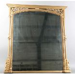A late Victorian gilt painted overmantel mirror with pierced foliate corner panels and spiral turned